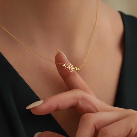 May include: A gold necklace with a heart charm and the name 'Alyssa' written in cursive script.